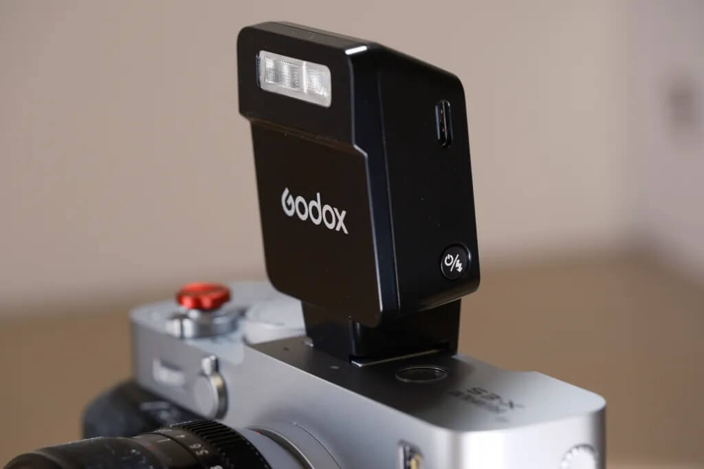 Бічна панель корпусу спалаху Godox iT22 з роз'ємом USB Type-C для заряджання та круглою увігнутою кнопкою ввімкнення й пілотного імпульсу