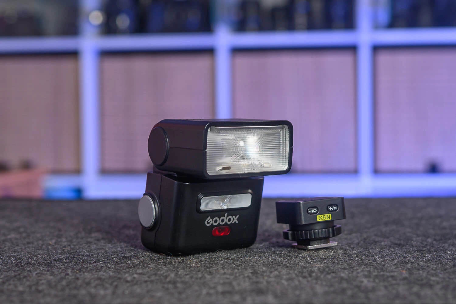Корпус спалаху Godox iT32 з повернутою праворуч голівкою і поруч окремий блок тригера з жовтою наклейкою X5N, двома кнопками на верхній грані та майданчиком башмака з рифленим кільцем.